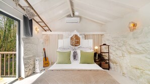 A bedroom with a large bed, a guitar, a wall-mounted heater, and a view of greenery outside. - Riverfront Retreat with Exclusive Waterfall Views (Baião)