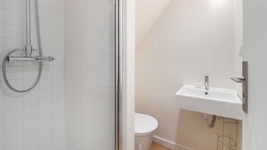 Une salle de bain avec douche, toilettes et lavabo.