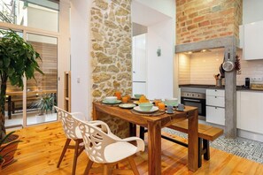 Una cucina moderna con parete in pietra, pavimento in legno e zona pranzo con tavolo apparecchiato per la colazione.