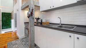Una cocina moderna con armarios blancos, encimera negra y estufa a la vista.
