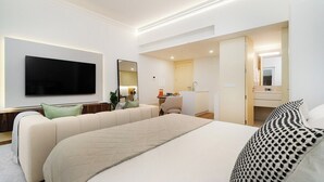 A modern hotel room with a large bed, a flat-screen TV mounted on the wall, a small desk with a chair, and a bathroom visible through an open door. - Modern Studio in Santa Catarina (Porto)