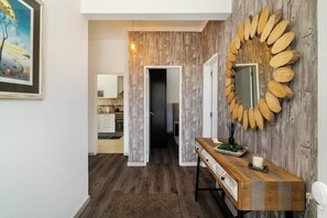 Un couloir avec un mur en bois, un miroir et une console sur laquelle est posée une bougie.