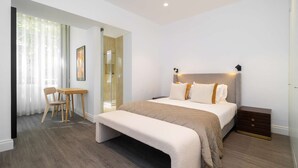 Un dormitorio moderno con cama, mesitas de noche, un banco, un escritorio y una silla.