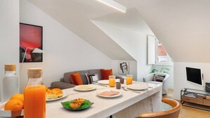 Une cuisine moderne avec un coin repas, dotée d’un plan de travail en marbre, d’un espace pour prendre le petit-déjeuner et d’un téléviseur fixé au mur.