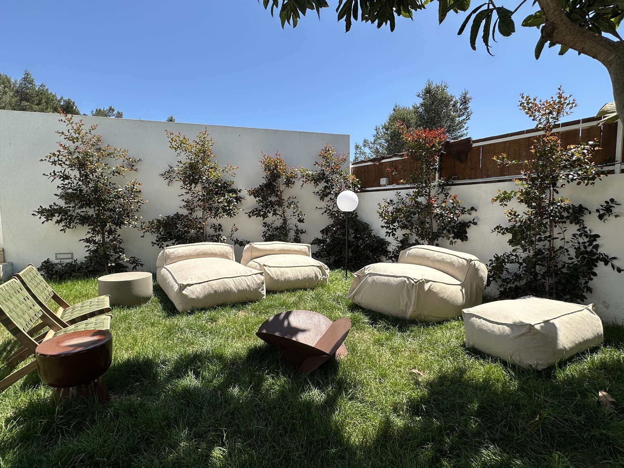 Ein Garten mit Gartenmöbeln, darunter Sofas und ein Tisch, umgeben von Gras und Bäumen.