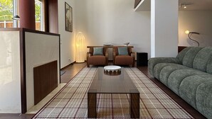 Ein modernes Wohnzimmer mit großem Fenster, einem Couchtisch, zwei Sofas und einer Stehlampe.