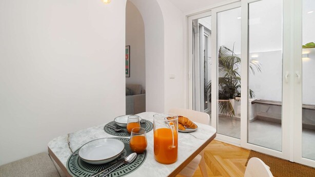 A dining area with a table set for two, including plates, glasses, and a pitcher of orange juice.