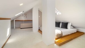A modern loft bedroom with a built-in bed, a wooden platform, and a sloped ceiling.