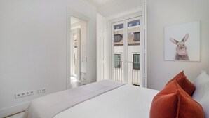 A bedroom with a bed, a door leading to a balcony, and a framed picture on the wall. - Timeless Design Meets Central Convenience (Lisbon)