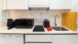 Een moderne keuken met witte kastjes, een zwarte magnetron, een broodrooster en een spoelbak.