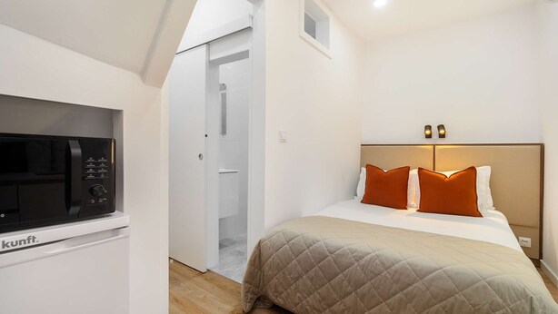 Ein Hotelzimmer mit einem Bett, einer Mikrowelle und einer Tür zu einem Badezimmer.