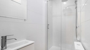 Ein modernes Badezimmer mit einer Duschkabine, einem weißen Waschbecken und einer Toilette.