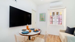 Un comedor con una mesa redonda, sillas y un televisor montado en la pared.