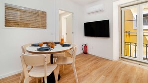 A dining area with a round table, chairs, and a television on the wall. - Modern Comfort Meets Old Lisbon Charm (Lisbon)