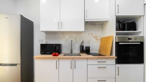 A modern kitchen with white cabinets, a black refrigerator, a microwave, a sink, and a Bosch oven. - Modern Comfort Meets Old Lisbon Charm (Lisbon)