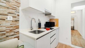 Une cuisine compacte dotée d’un pare-feu en pierre, d’un évier en acier inoxydable et d’un four à micro-ondes.