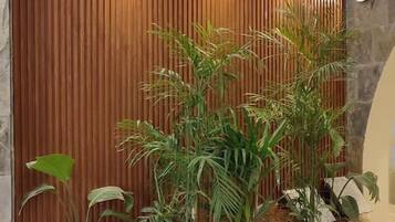 Ein modernes Interieur mit einer Holzwand, einem Betongartentopf mit tropischen Pflanzen und einer Steinwand.