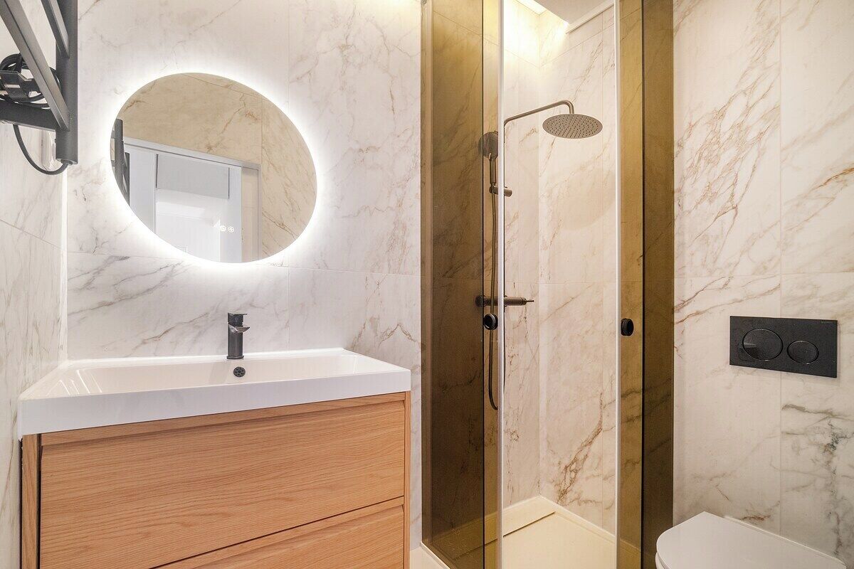 Une salle de bain moderne avec un meuble-lavabo en marbre, une douche à parois de verre et des toilettes.