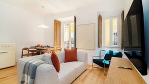 Una sala de estar moderna con un sofá, una mesa de comedor y un televisor.