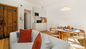 Un espace de vie compact comprenant un canapé, une table à manger et une kitchenette.