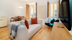 A modern living room with a sofa, a dining table, and a TV. - Live Like a Local in Vibrant Bairro Alto (Lisboa)