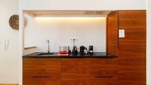 Eine kleine Küche mit schwarzer Arbeitsplatte, Holzschränken, einer Edelstahlspüle und einer Kaffeemaschine.