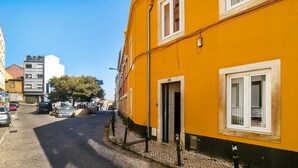 Eine enge Kopfsteinpflasterstraße, gesäumt von Gebäuden, darunter ein markantes gelbes Gebäude mit einer Tür und einem Fenster.