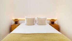 A neatly made bed with two pillows, a bedside lamp, and a wooden nightstand. - Lisbon Charm: Walk to Graça Viewpoints (Lisbon)
