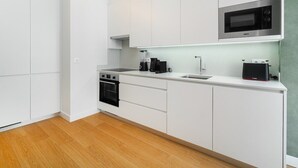 A modern kitchen with white cabinetry, a built-in oven, a microwave, and a coffee machine. - Light-Filled Studio with a True Neighborhood Feel (Lisbon)