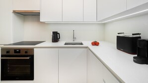 Eine moderne Küche mit weißen Schränken, einem eingebauten Ofen, einer Kaffeemaschine und einem Toaster.