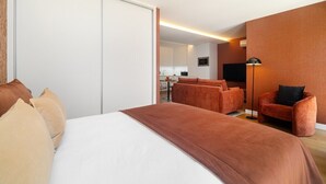 Ein Hotelzimmer mit einem Bett, einem Schlafsofa, einem Sessel, einem Schreibtisch und einem Fernseher.