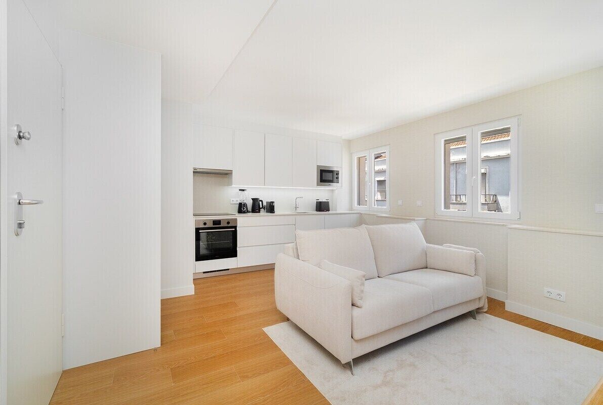 Un appartement moderne doté d’une kitchenette, d’un canapé et d’une grande fenêtre.