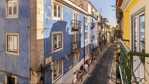 A narrow street flanked by buildings with blue patterned facades and a yellow building on the right. - Old Town Flat with a Modern Touch (Lisbon)