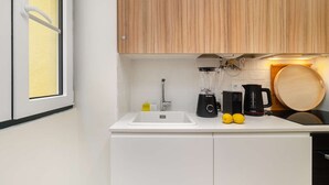 A kitchen with white cabinets, a Bosch blender, a coffee maker, and lemons on the counter. - Old Town Flat with a Modern Touch (Lisbon)