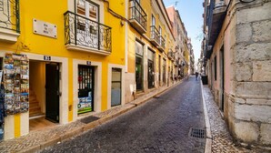 A narrow street lined with yellow buildings, some with balconies and signage. - Old Town Flat with a Modern Touch (Lisbon)