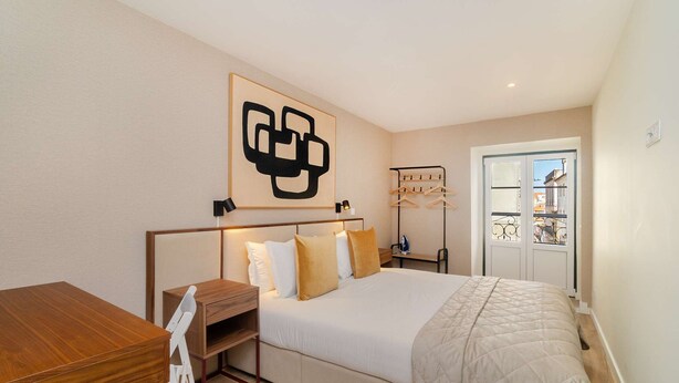 A bedroom with a bed, bedside table, chair, and a wall-mounted artwork. - Old Town Flat with a Modern Touch (Lisbon)