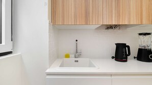 A kitchen with white countertops, a sink, a Bosch coffee maker, and a blender. - Old Town Flat with a Modern Touch (Lisbon)
