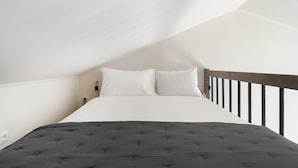 A bedroom with a bed, white pillows, a dark grey duvet, and a wooden headboard. - Sunny Studio Stay in Central Oeiras (Oeiras)