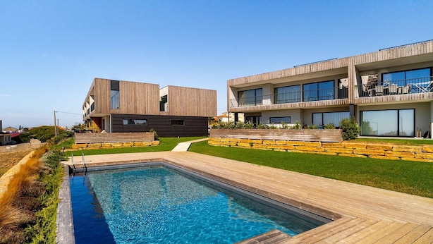 Un complexe résidentiel moderne doté d’une piscine, d’une terrasse en bois et de murs de soutènement en pierre.