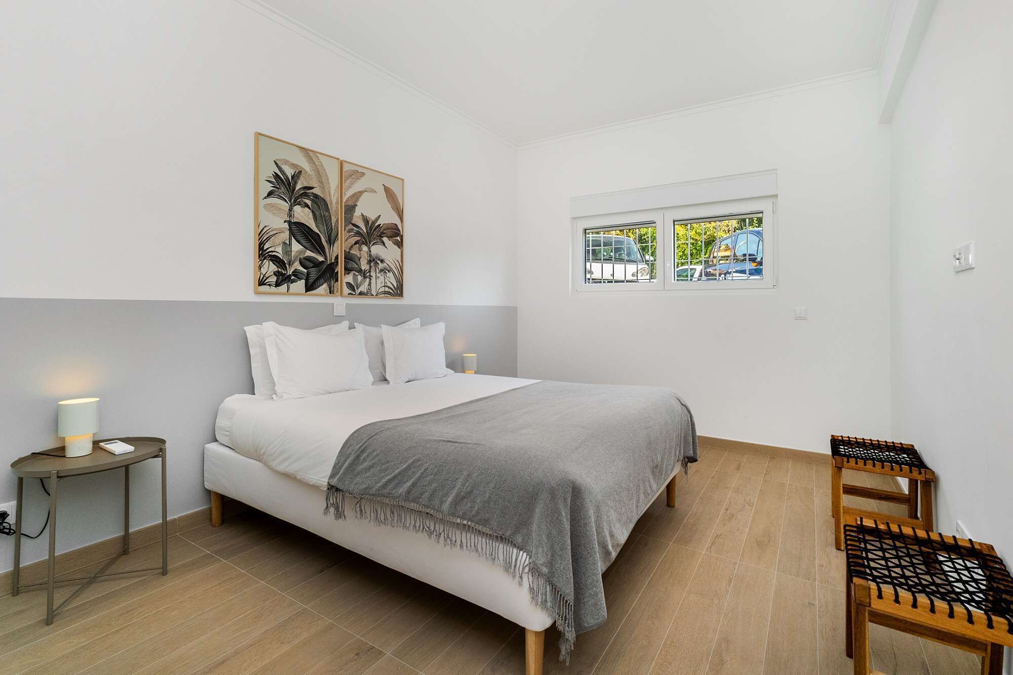 Une chambre à coucher comprenant un lit, une table de chevet, une chaise, une fenêtre et des œuvres d’art murales.