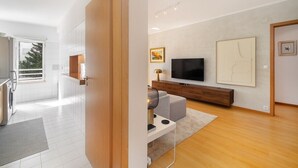 A modern living room with a flat-screen TV, a wooden cabinet, and a painting on the wall. - Modern Apartment with Great Atmosphere (Lisbon)