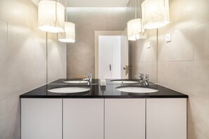 Ein modernes Badezimmer mit zwei Waschbecken, schwarzen Arbeitsplatten und weißen Schränken.