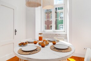 A round dining table with plates, cutlery, and glasses set for breakfast. - Elegant Lisbon Flat in a Top-Notch Location (Lisbon)