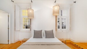Un dormitorio con una cama grande, dos lámparas colgantes y vistas al exterior a través de una ventana.