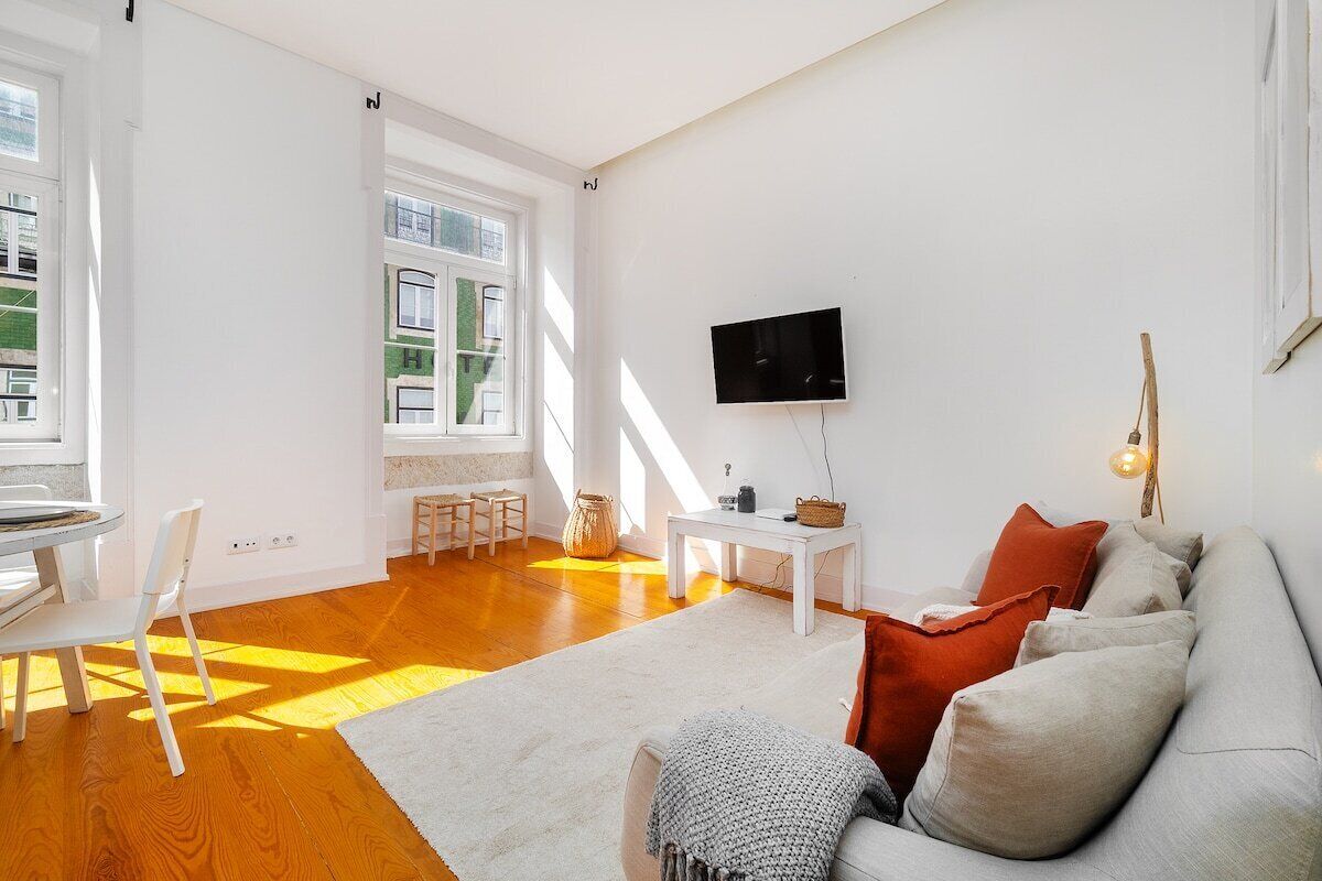 Ein heller Wohnraum mit einer Couch, einem Fernseher und einem Tisch.