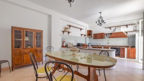 A spacious kitchen with a dining area, featuring a wooden cabinet, a glass-top table, and a modern stove. - Nice home in Gioiosa Marea (Gioiosa Marea)