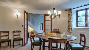 A dining area with a round table, wooden chairs, and a chandelier.