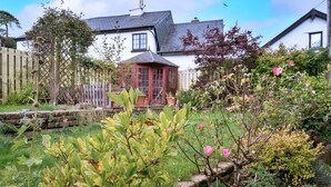 A garden with a wooden fence, a red-roofed structure, and various plants.