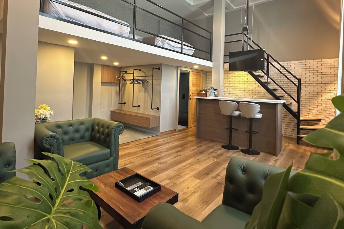A spacious loft with a mezzanine bedroom, a kitchen area, and a seating area with a coffee table.