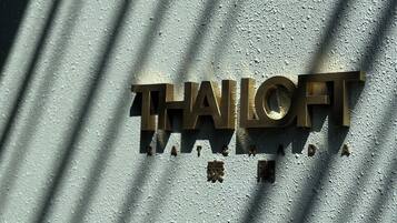 Een metalen bord met de tekst 'THALFT' en Chinese karakters op een gestructureerde muur.